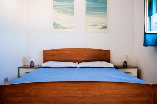 a bedroom with a wooden bed with a blue blanket at Attico De Gasperi in Orosei