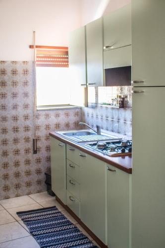 a kitchen with white cabinets and a stove top oven at Attico De Gasperi in Orosei
