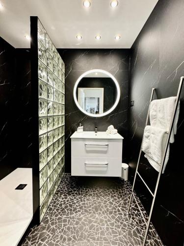 une salle de bain noire avec un lavabo et un miroir dans l'établissement Vue exceptionnelle début Cap Corse La Pier Noire, à San-Martino-di-Lota