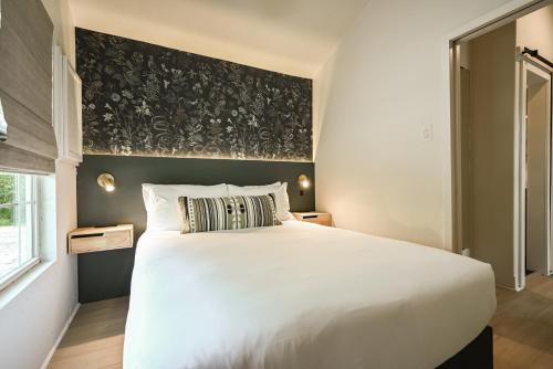 a bedroom with a large white bed and a wall at Melrose River Club Resort in San Marcos