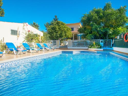 Villa Honolulu by Algarve Vacation في ألبوفيرا: مسبح وكراسي الصالة الزرقاء بجانب مبنى