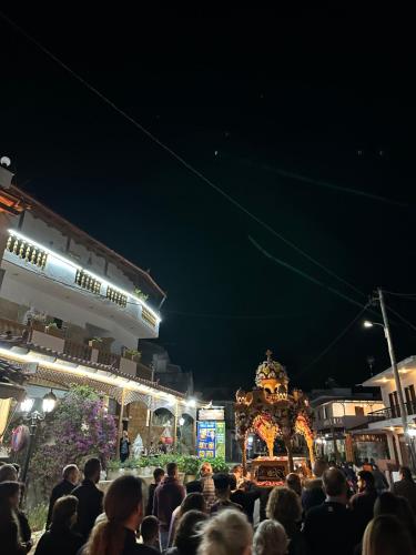 una multitud de personas de pie en frente de un mercado por la noche en Costas Inn, en Spílion