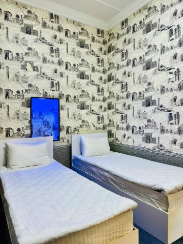 - 2 lits dans une chambre avec un mur orné d'une fresque murale représentant des moutons dans l'établissement SHUKRONA Hotel, à Samarcande