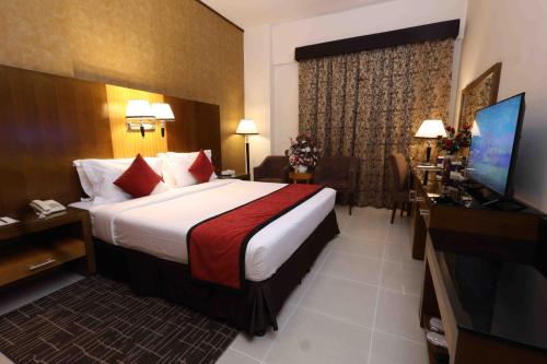 a hotel room with a bed and a flat screen tv at City Tower Hotel in Fujairah