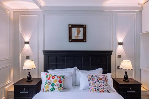 a bedroom with a bed with pillows and two lamps at Lavermo Hotel Apartments in Kampala