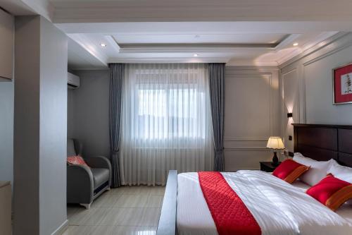 a bedroom with a bed and a chair and a window at Lavermo Hotel Apartments in Kampala