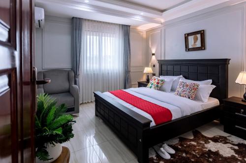 a bedroom with a large bed and a chair at Lavermo Hotel Apartments in Kampala