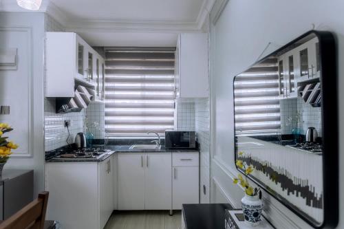 a kitchen with white cabinets and a sink and a window at Lavermo Hotel Apartments in Kampala