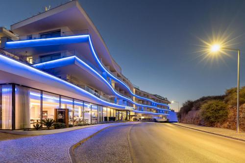 een gebouw met blauwe lichten aan de kant van een weg bij Jupiter Marina Hotel - Couples & Spa in Portimão