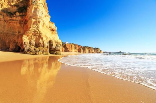 a beach with a large cliff and the ocean at Jupiter Marina Hotel - Couples & Spa in Portimão