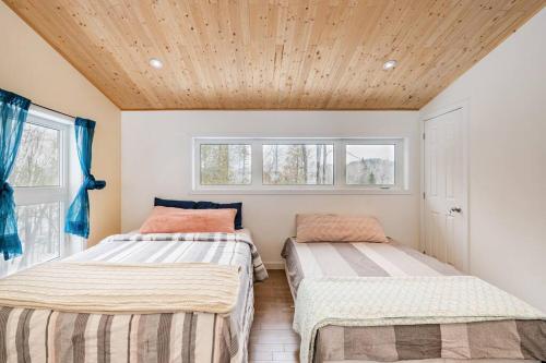 two beds in a room with a wooden ceiling at Les aurores in Harrington