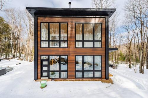 a tiny house with a black roof in the snow at Les aurores in Harrington