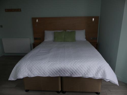 a large bed with white sheets and green pillows at Hamilton Court Hotel in Chester