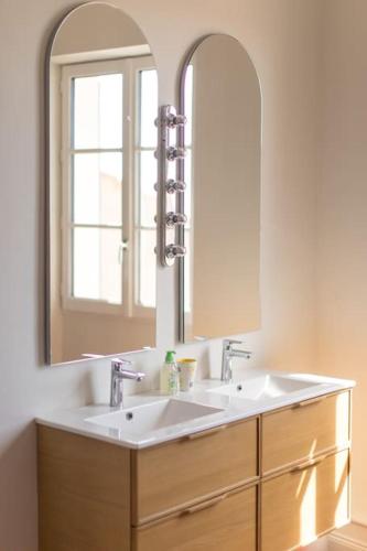 une salle de bain avec un lavabo et un grand miroir dans l'établissement Superbe maison T3 vue mer & jardin, à Hyères