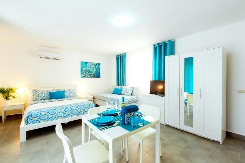 um quarto branco com uma cama, uma mesa e uma cama em TROPICANA SUITES DELUXE BEACH CLUB and POOL - playa LOS CORALES em Punta Cana