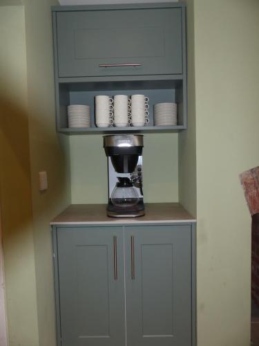 a cabinet with cups and plates on top of it at Hamilton Court Hotel Hoole in Chester