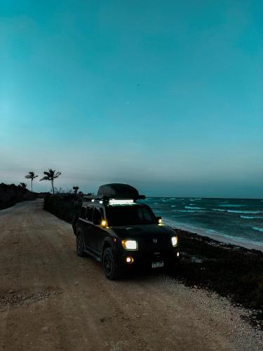 un jeep estacionado en un camino de tierra junto al océano en Mini Camper Honda Element, en Guatemala