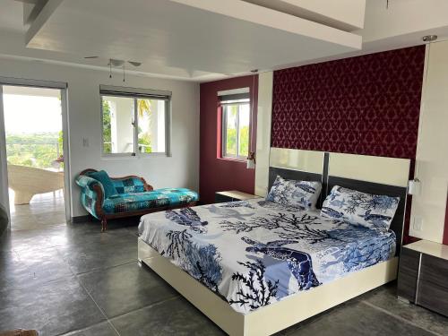 a bedroom with a king sized bed and a chair at Casa vista al mar y las montañas río san Juan a solo 4 minutos de centro del pueblo y las playas in Río San Juan