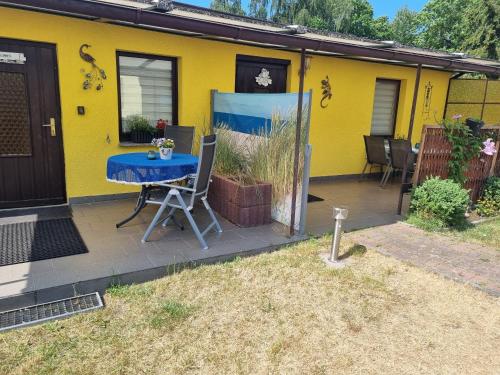 een patio met een blauwe tafel en een geel huis bij Pension Wiesenperle in Trassenheide