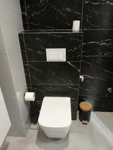 Łazienka z białą toaletą i czarną ścianą w obiekcie Apartament Diament 2 - Jezioro Nyskie w Nysie