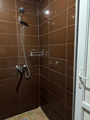 y baño con ducha de azulejos marrones. en Отель «JIMA” en Kobuleti