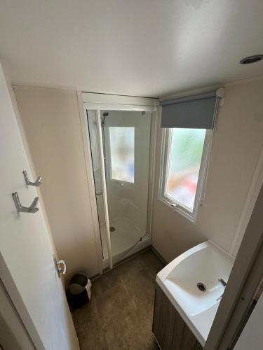 une salle de bain blanche avec un lavabo et une douche dans l'établissement Mobil-home bord de mer, à Vendres