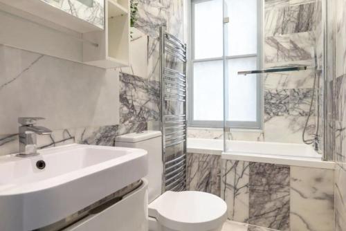 een badkamer met een wastafel, een toilet en een raam bij Stylish Apt - Newly refurbished - Private Terrace in Londen