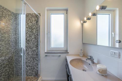 a bathroom with a sink and a shower and a mirror at Riviera Beach House in Calceranica al Lago