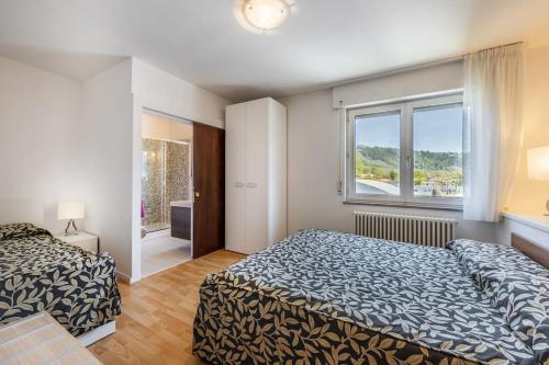 a bedroom with two beds and a window at Riviera Beach House in Calceranica al Lago