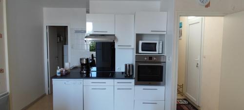 une cuisine avec des armoires blanches et des appareils noirs dans l'établissement APPARTEMENT Rue des NENUPHARS ST HILAIRE DE RIEZ, à Saint-Hilaire-de-Riez
