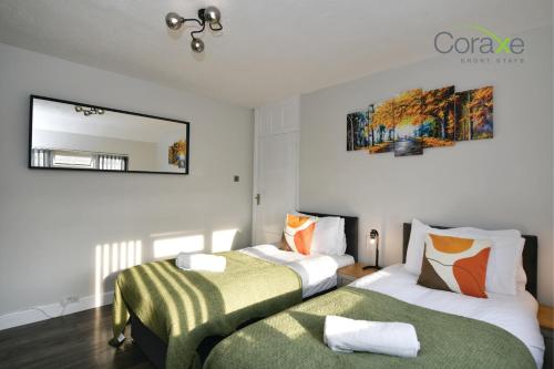 1 Schlafzimmer mit 2 Betten und einem Wandspiegel in der Unterkunft 3 Bedroom Blissful Living for Contractors and Families Choice by Coraxe Short Stays in Tilbury
