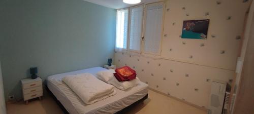 - une petite chambre avec un lit doté d'un oreiller rouge dans l'établissement APPARTEMENT Rue des NENUPHARS ST HILAIRE DE RIEZ, à Saint-Hilaire-de-Riez