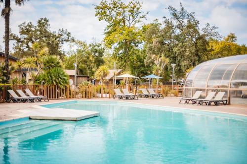 a swimming pool with chaise lounge chairs and a domed building at Les Maritimes in Seignosse