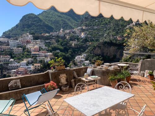 eine Terrasse mit Tischen und Stühlen und Stadtblick in der Unterkunft Palatonella in Positano