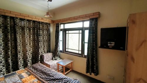 1 Schlafzimmer mit einem Bett, einem Fenster und einem TV in der Unterkunft Hostel Inn Srinagar in Srinagar