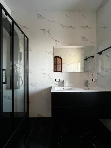 bagno bianco con lavandino e specchio di Casa vacanza La casa delle Onde a Torrenova