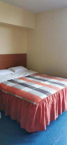 a bedroom with a bed with a red blanket on it at Hostal President in Lima