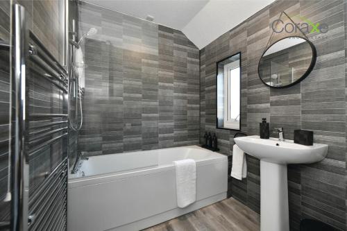 uma casa de banho com uma banheira branca e um lavatório. em 3 Bedroom Blissful Living for Contractors and Families Choice by Coraxe Short Stays em Tilbury