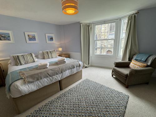 a bedroom with a bed and a chair and a window at Rose Cottage - Central Dartmouth in Dartmouth