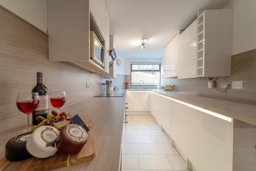 a kitchen with white cabinets and wine glasses on a table at Kirkmoor Cottage - Cosy home central Clitheroe in Clitheroe