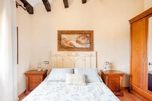 um quarto com uma cama branca com duas mesas de cabeceira em Masia Castellvi em Vinyols i els Arcs