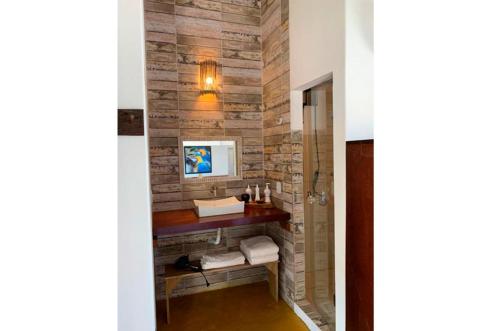 a bathroom with a stone wall with a wooden table at Pousada Cores do Mar Caraíva in Caraíva