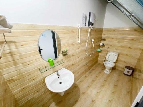 ein Badezimmer mit einem Waschbecken, einem Spiegel und einem WC in der Unterkunft Trung Nghĩa Villa 20 in Da Lat