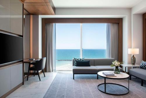 a living room with a couch and a television with the ocean at The David Kempinski Tel Aviv in Tel Aviv