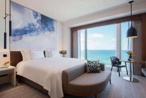 a bedroom with a bed and a chair and a large window at The David Kempinski Tel Aviv in Tel Aviv