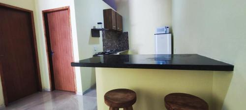 uma cozinha com um balcão preto e dois bancos em Casa Amarela em São Miguel dos Milagres