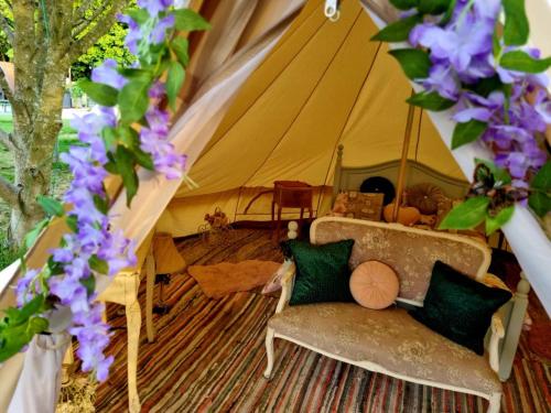 a tent with a couch in a room with purple flowers at French Tent secret garden glamping in Newark-on-Trent