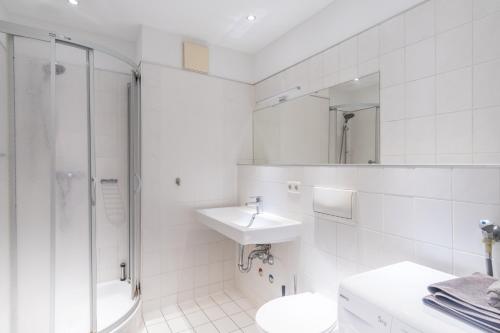 uma casa de banho branca com um lavatório e um chuveiro em Arbeitsplatz, Tiefgaragenstellplatz, 4k TV Netflix em Leipzig