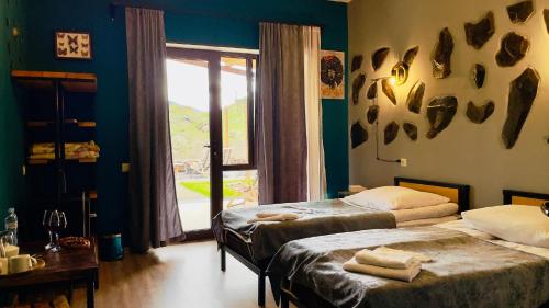 1 dormitorio con 2 camas y ventana con vistas en Hotel Hobbiton near Vardzia Caves, en T'mogvi