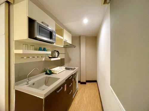 eine kleine Küche mit Spüle und Mikrowelle in der Unterkunft Arawana Express Phromphong in Bangkok